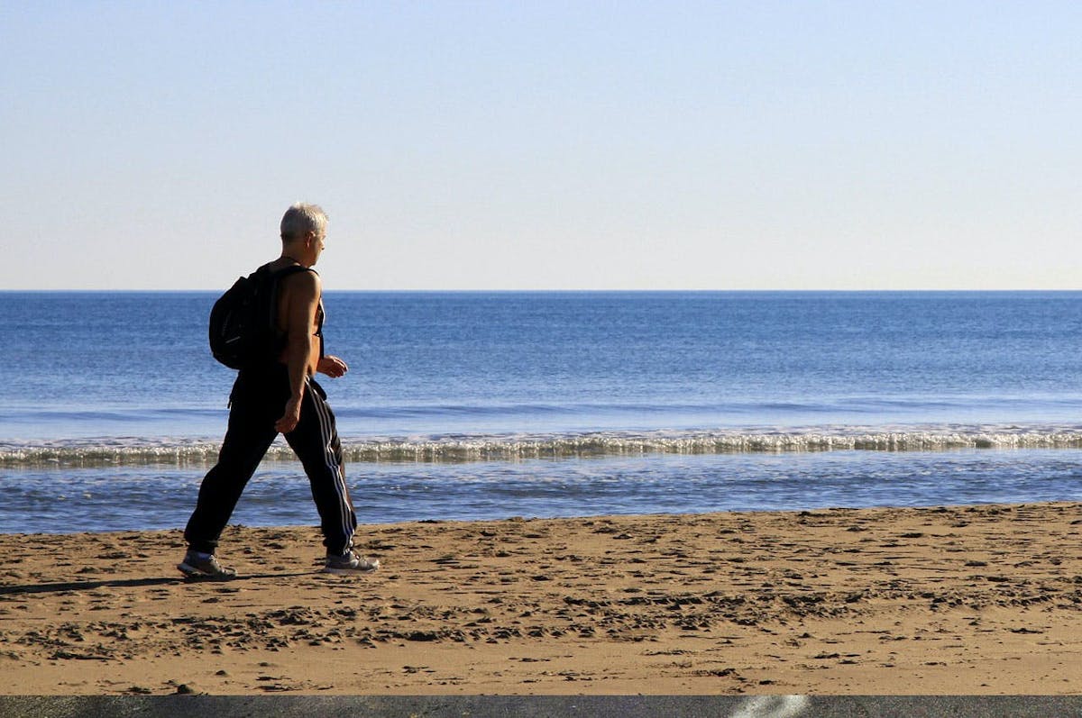 Middle-aged man walking by the beach sand