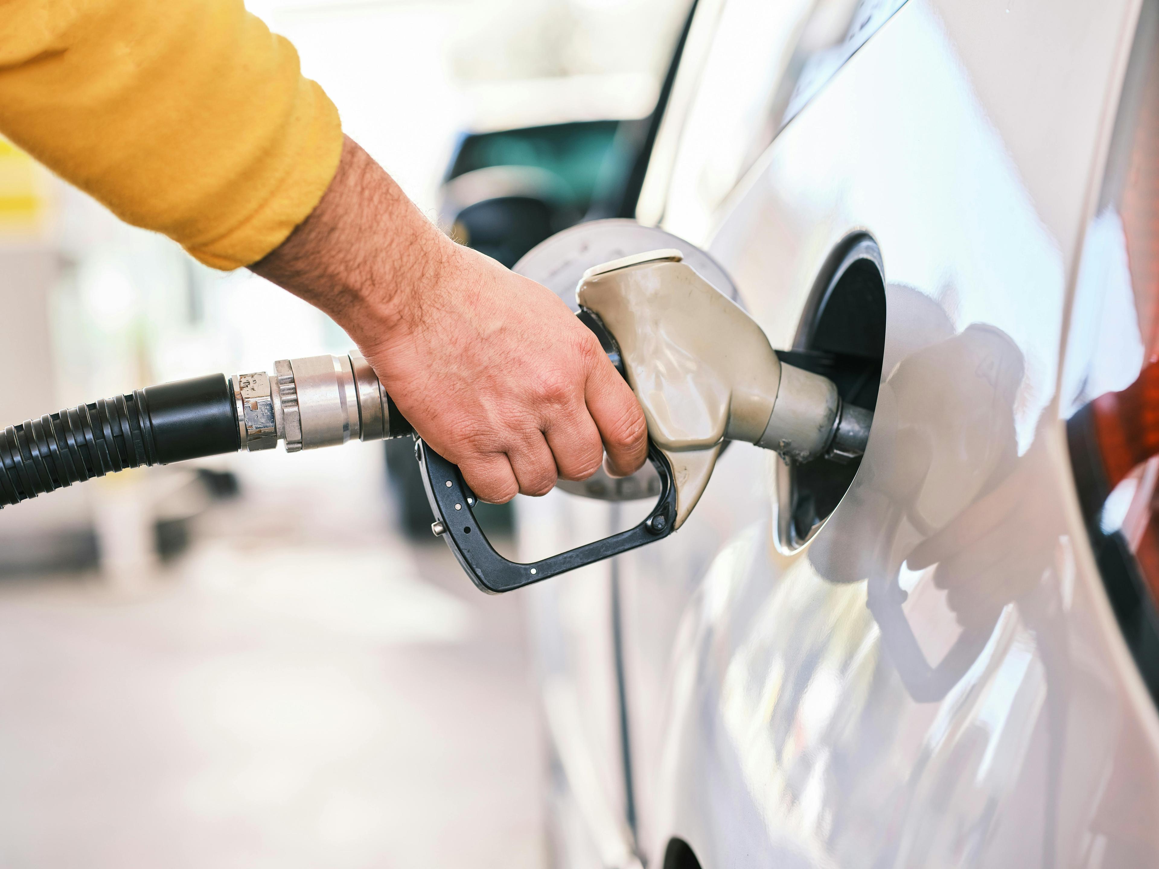 Closeup of man pumping gasoline fuel in car at gas station.