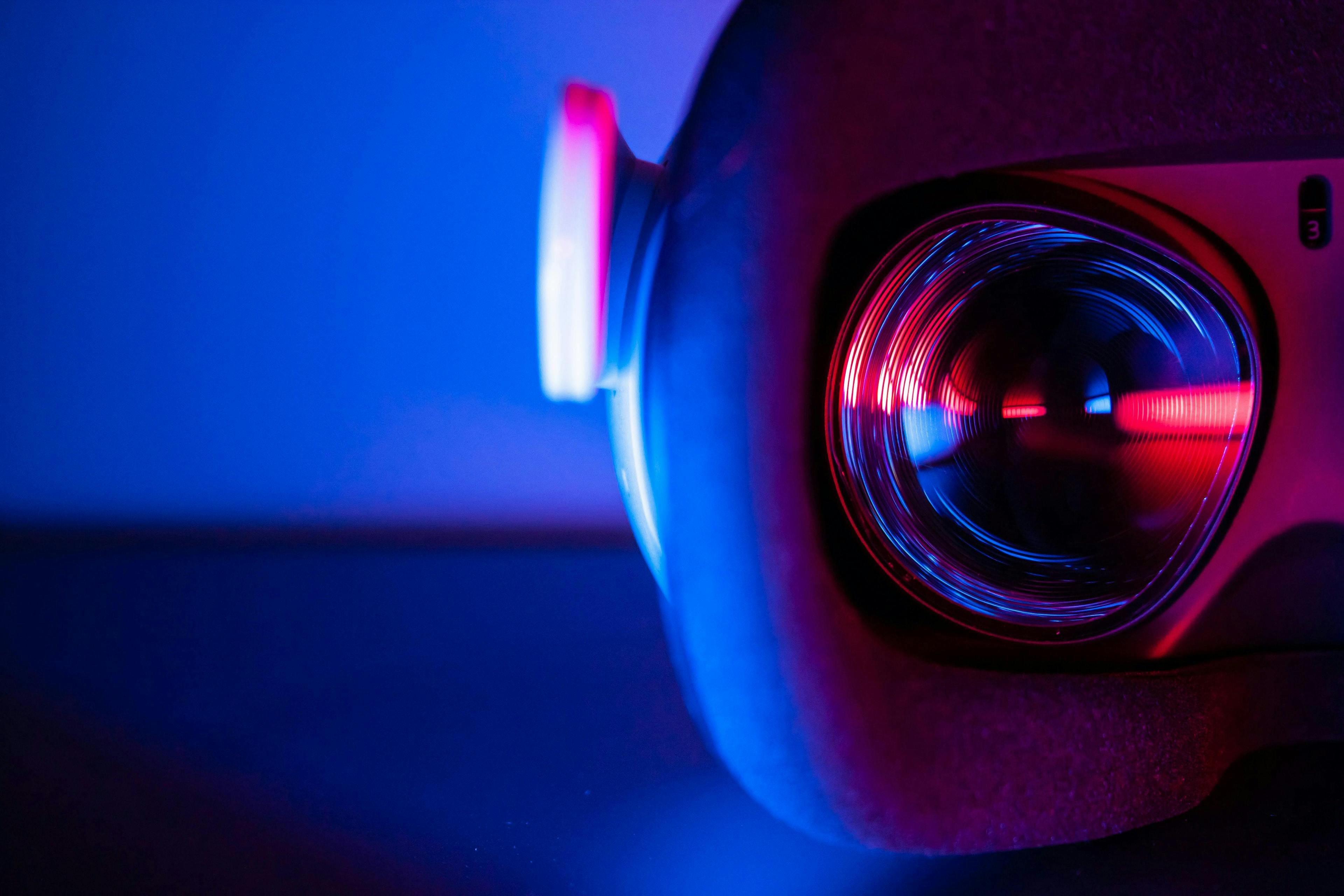 A close-up of a virtual reality headset lens glowing with red and blue lights, set against a dark background.