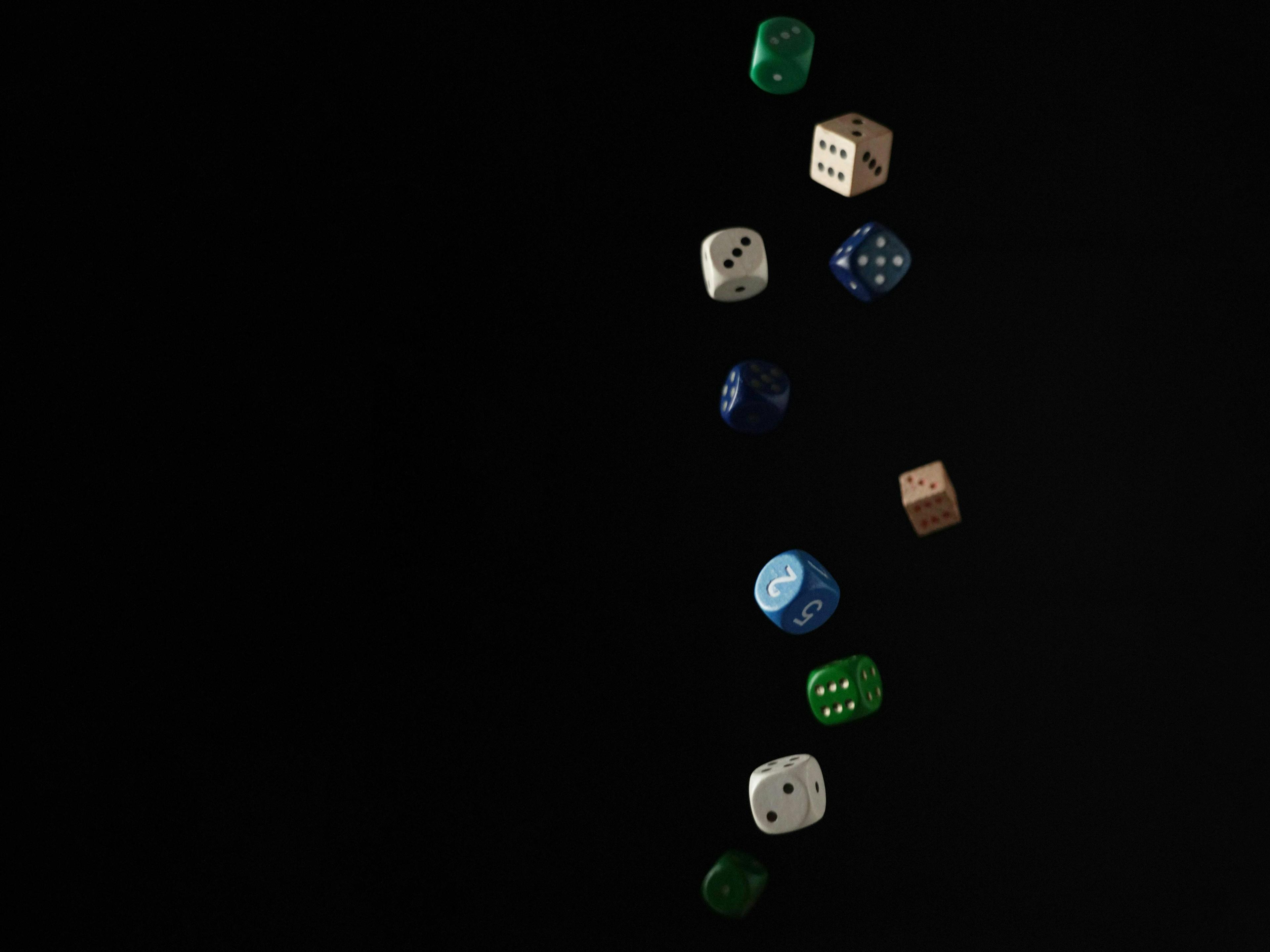 Various colored dice are suspended mid-air against a black background, showing numbers and dots in a seemingly random arrangement.
