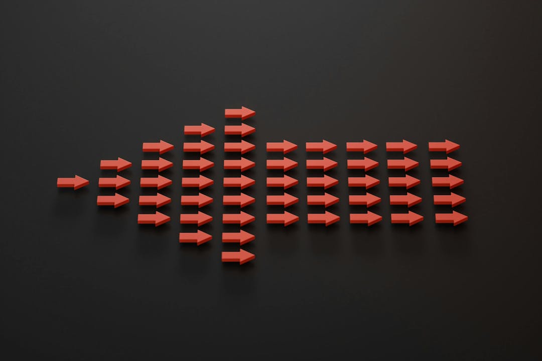 Red arrows arranged in a triangle, pointing right, on a black background. The arrows increase in number from left to right, creating a pattern that resembles a bar graph or sound wave.