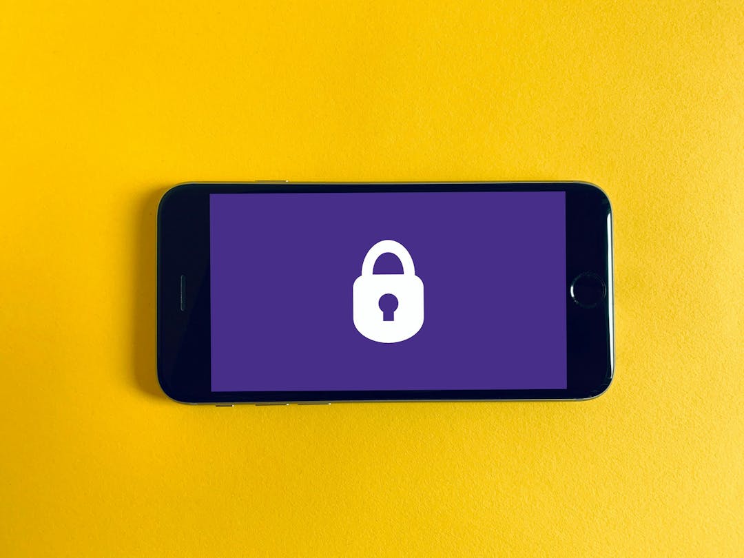a phone that has a purple wallpaper with a white lock icon - on top of a yellow background