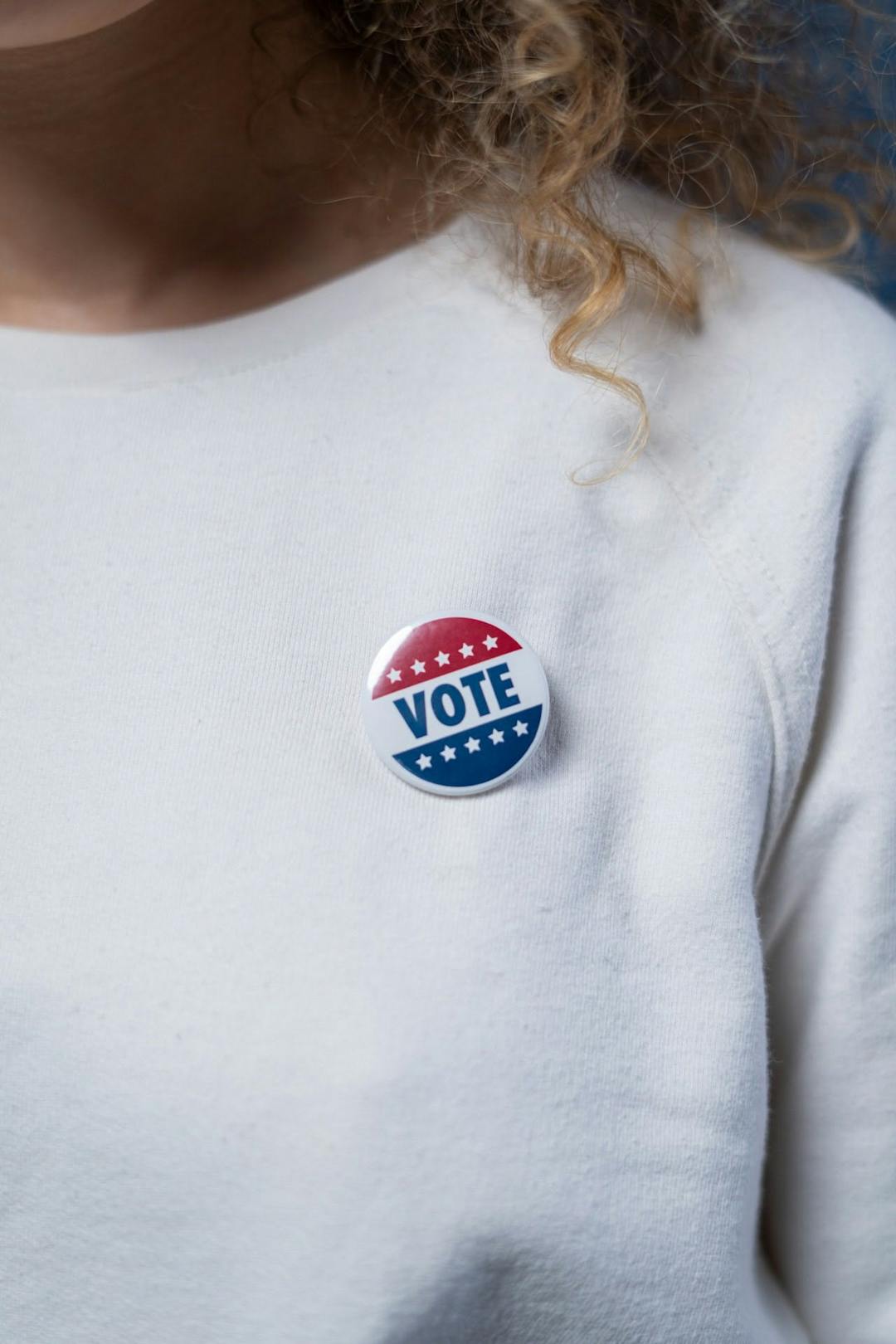 white sweater with a vote pin