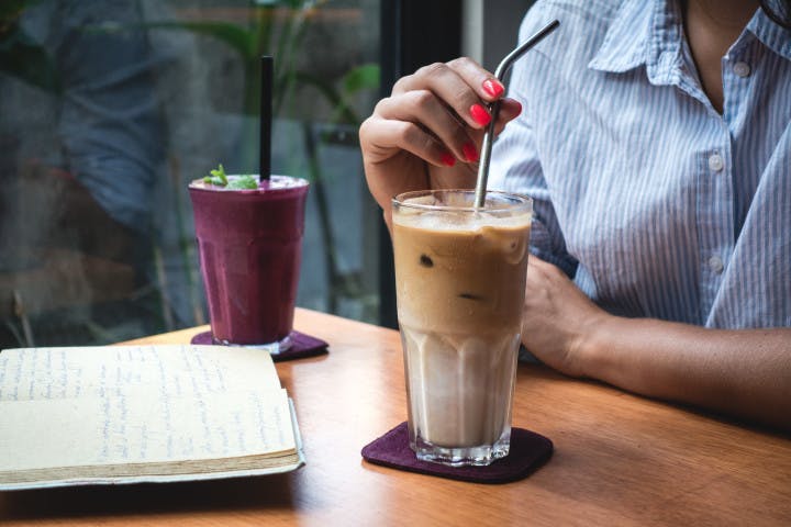 woman holding a straw in a glass filled with coffee