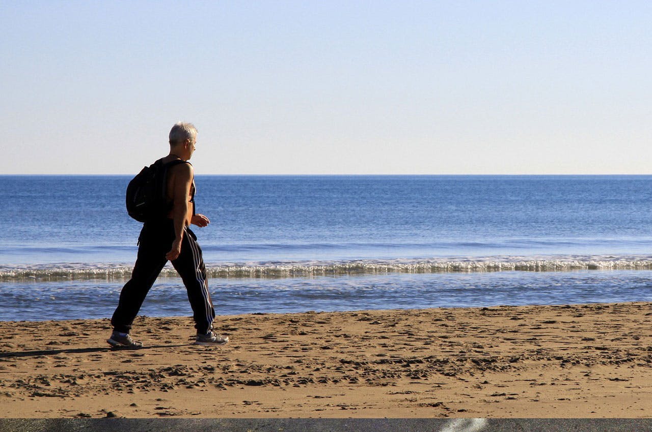 Middle-aged man walking by the beach sand