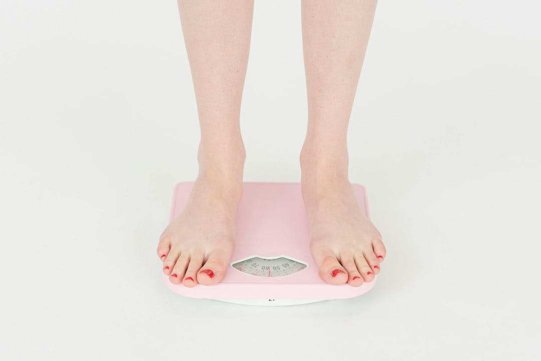 person with painted toenails standing on pink scale