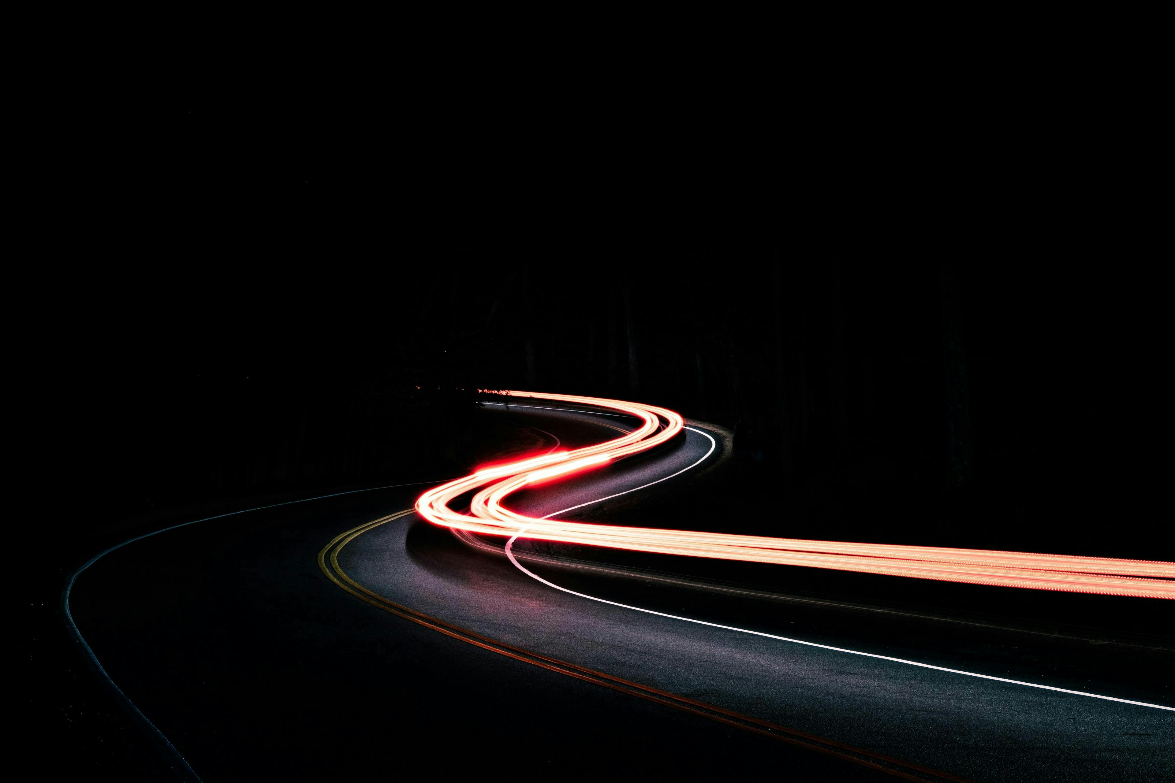 A long-exposure photo of a motor vehicle driving at night.