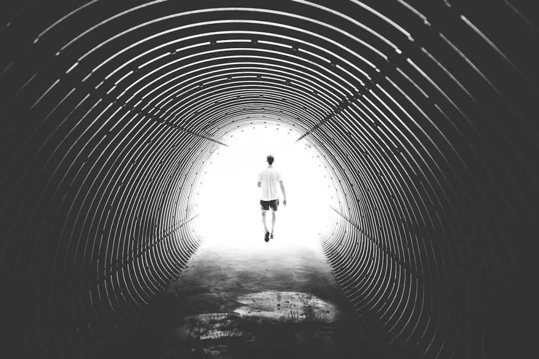 man walking out a tunnel