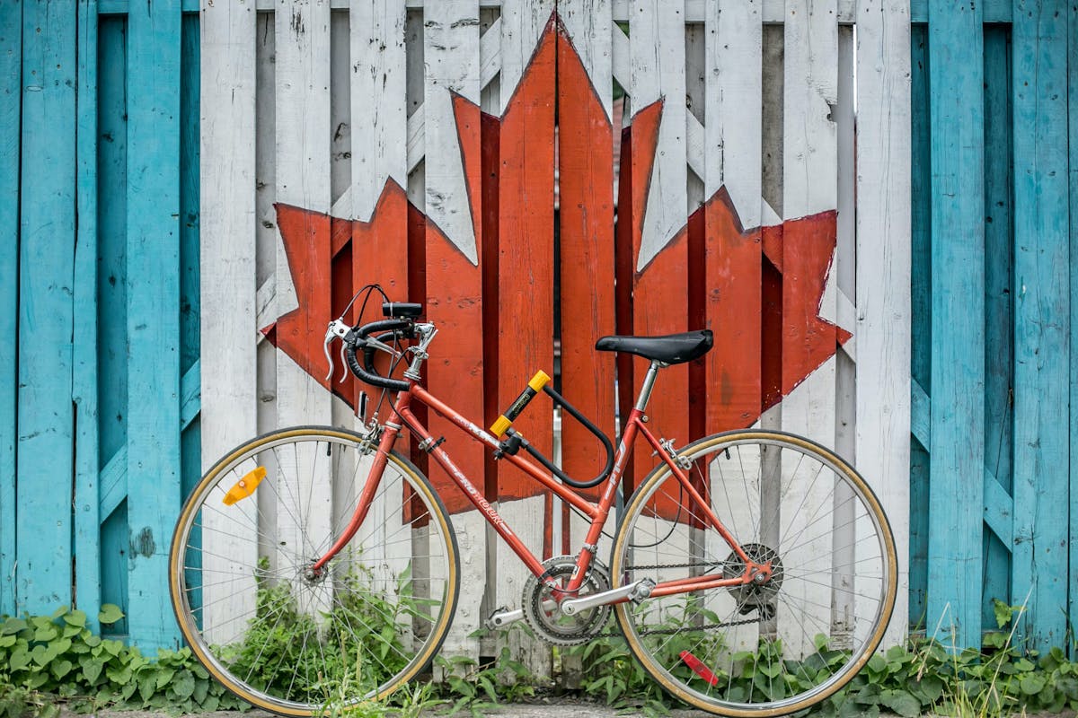 a ride bike against a wooden fence that is painted with the Canadian flag