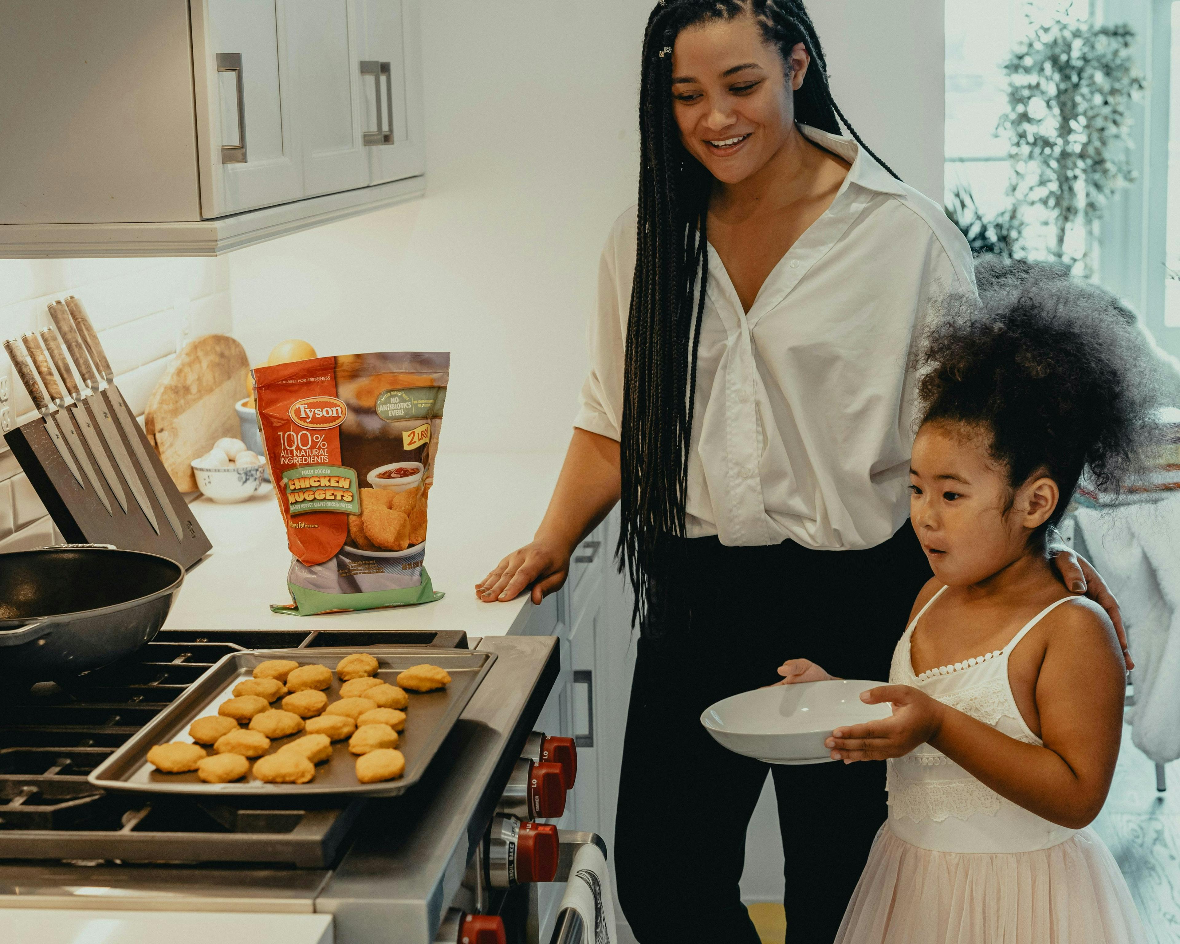 woman and child cooking chicken nuggets