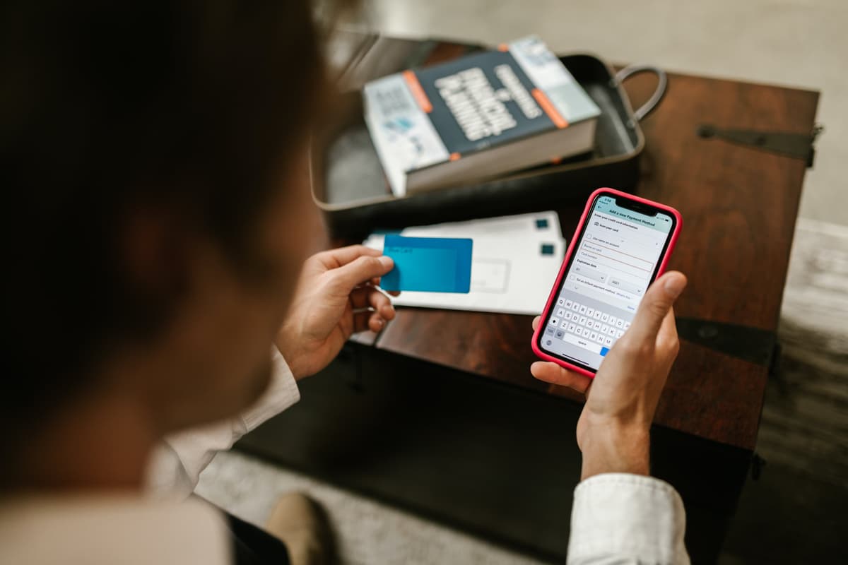 Person holding phone and credit card to buy ticket